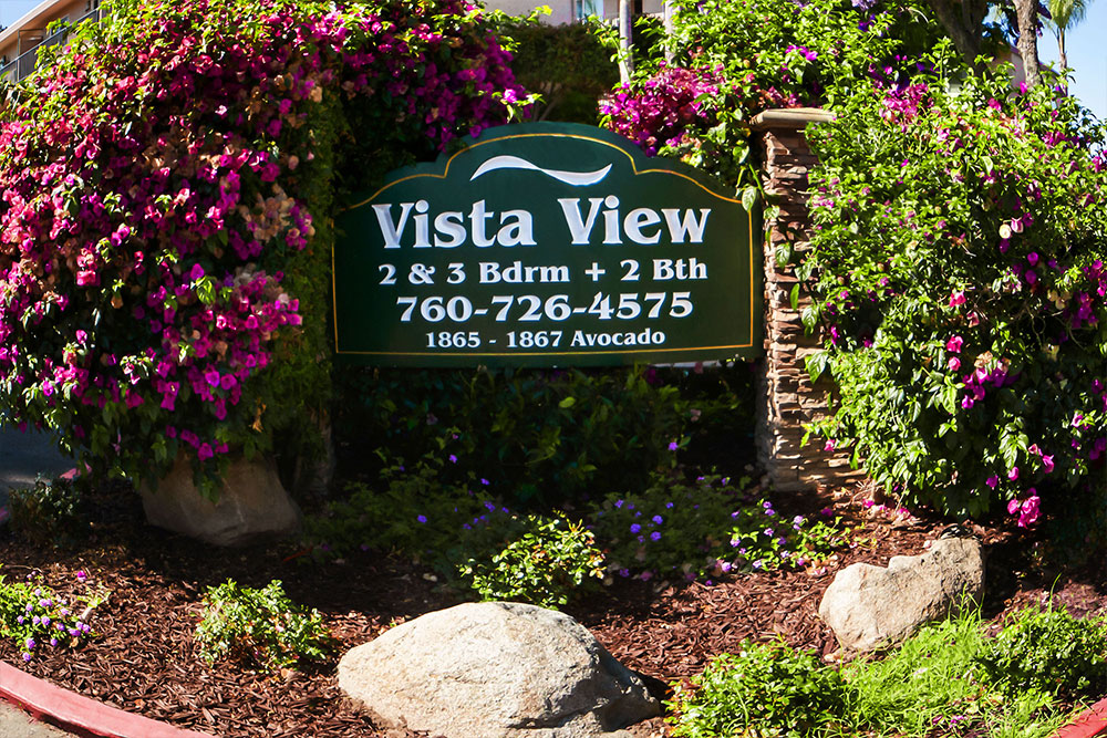 ista View Apartments monument sign surrounded by purple flowers and green landscaping.